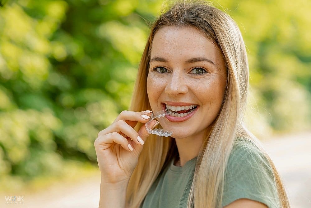 a woman holding invisalign close to her mouth as as one of the Alternatives to Braces in Prosper, TX.