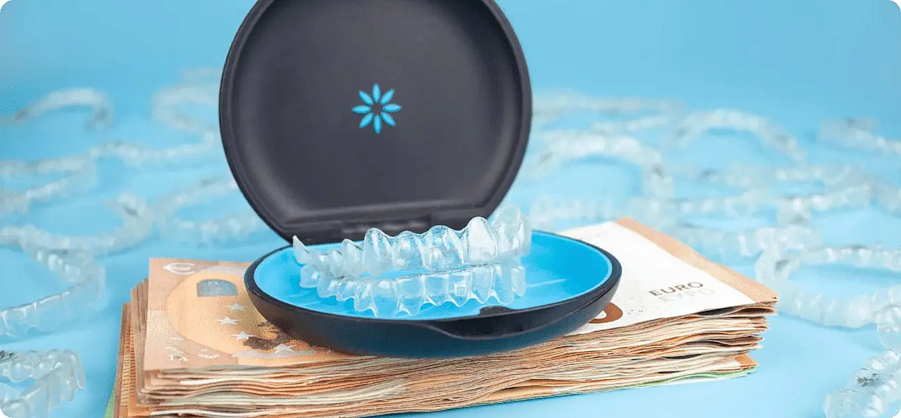 Against a blue backdrop, clear dental aligners in an open case sit atop euro banknotes, with more aligners scattered nearby. This scene subtly suggests the Invisalign cost at Winks Orthodontics
in Prosper and Colleyville, TX