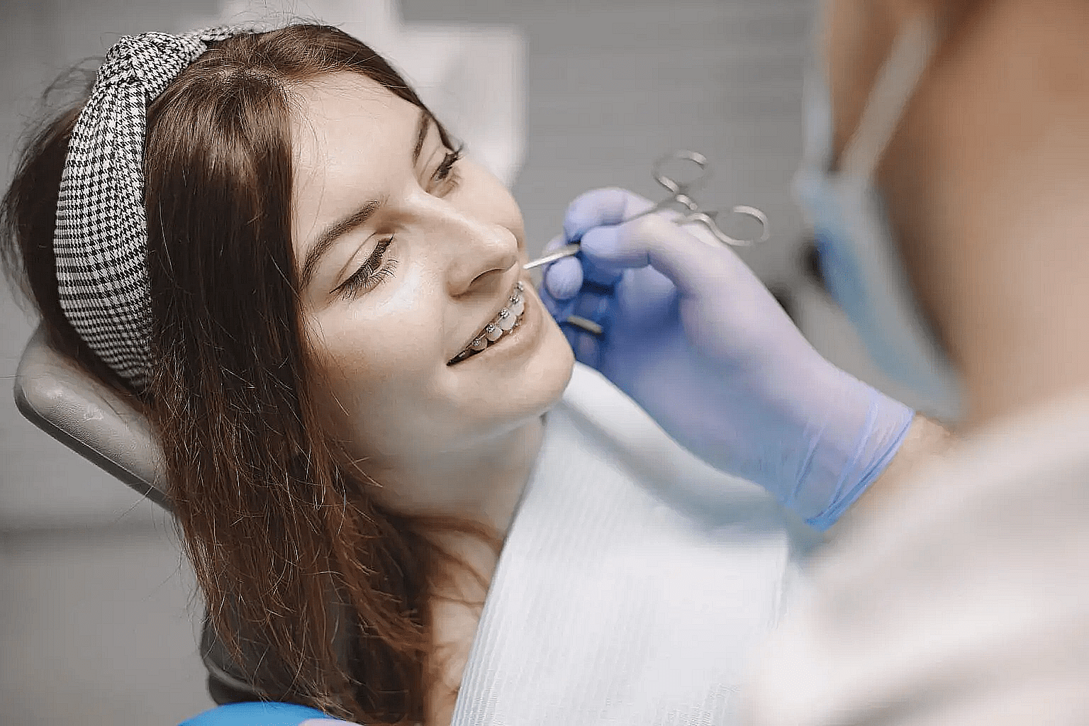 At Wink Orthodontics in Colleyville, TX, a gloved dentist examines a smiling young woman with braces.