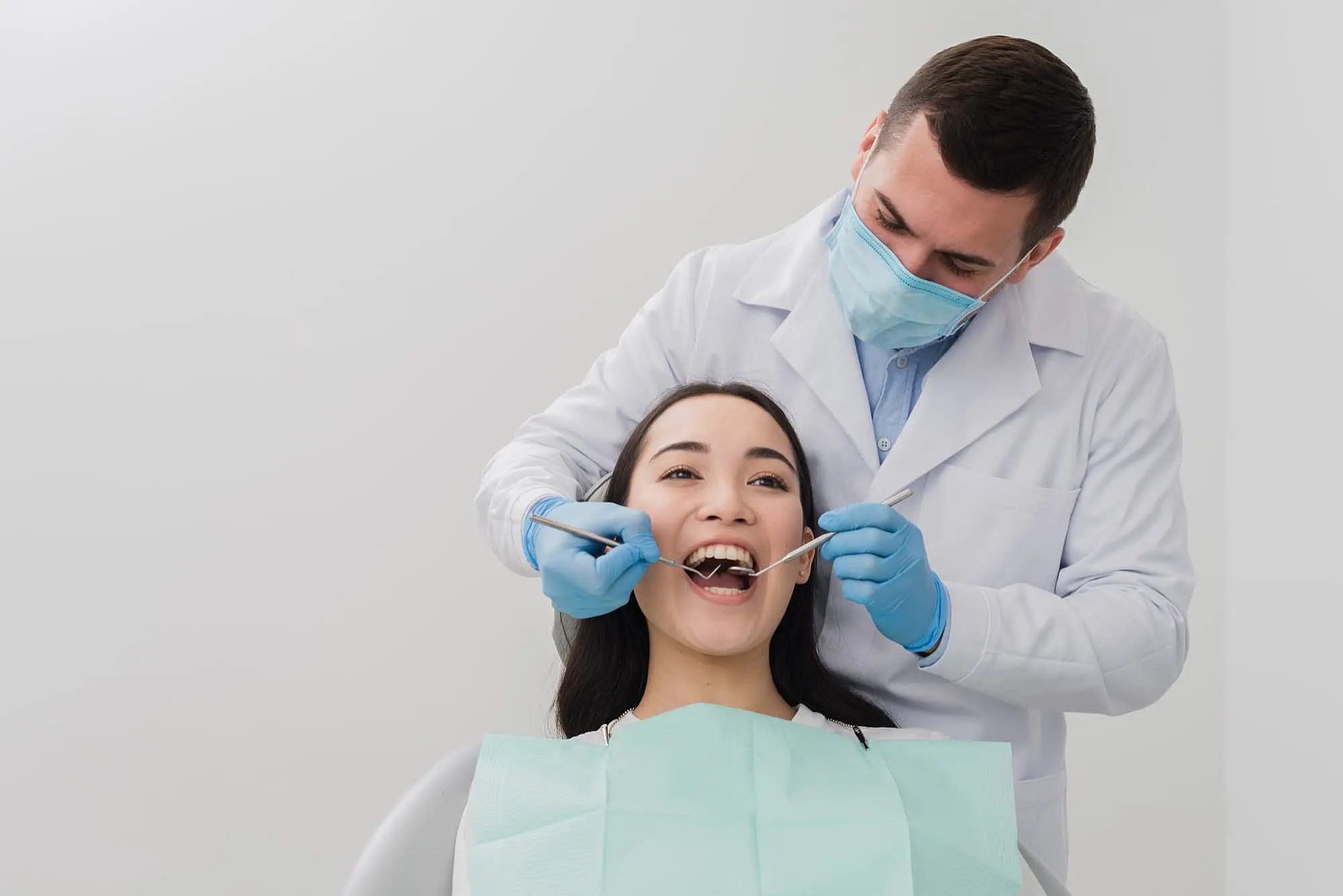 A dentist in a mask examines a mouth breather teeth using a dental tool in the clinic. The patient is reclined comfortably in the dental chair in Prosper or Colleyville, TX