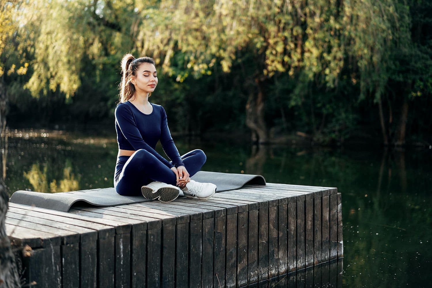 A person practicing yoga indoor, sitting cross-legged in a meditation pose, surrounded by greenery, embraces tranquility as the gentle breeze offers a break from the chaos of being a mouth breather in everyday life in Prosper or Colleyville, TX