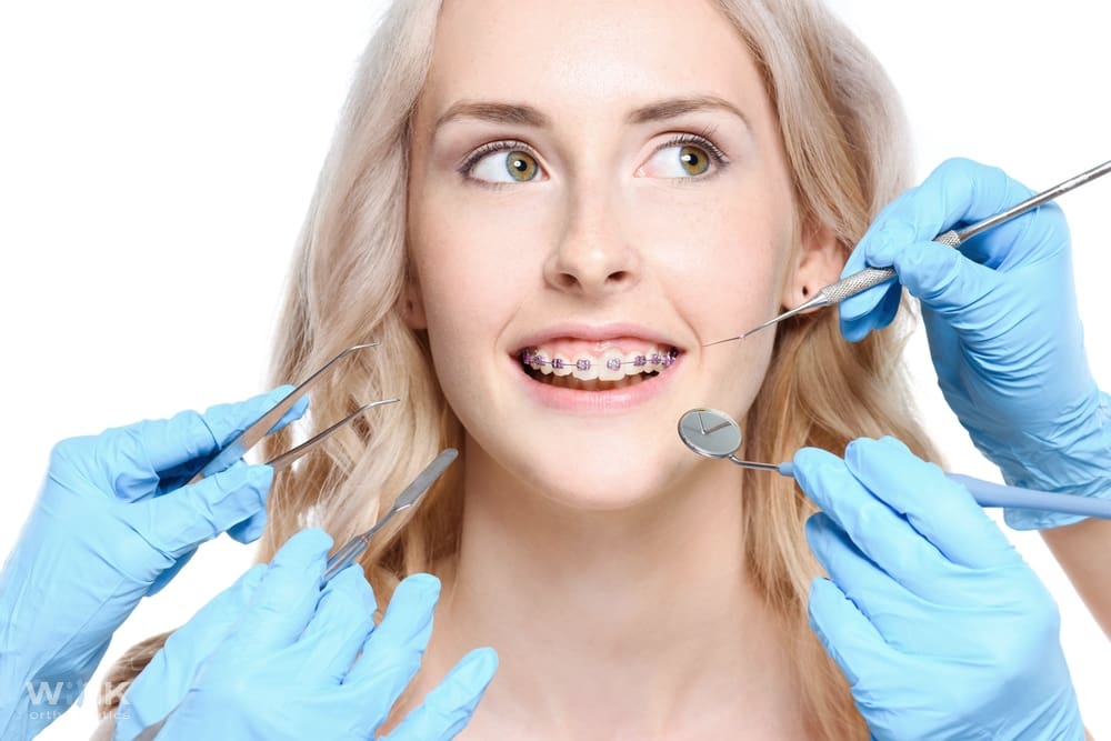 Orthodontist examining a young woman with braces during a dental checkup – braces for overbite in prosper and colleyville, tx.