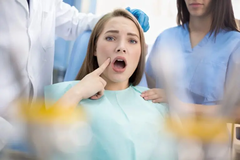 Young child sitting in a dental chair with mouth open while a dentist and assistant work nearby - TMJ Treatment in Prosper and Colleyville, TX