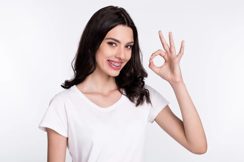 a woman showing OK hand sign to the camera after from an orthodontist in Colleyville, TX