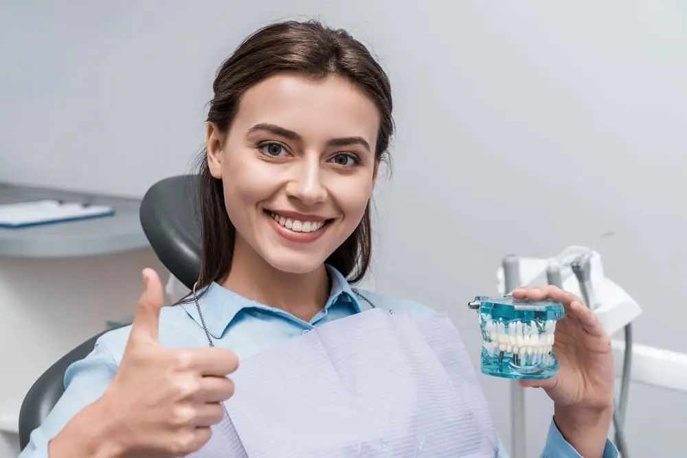 a patient of an orthodontist in Colleyville, TX holding a teeth model