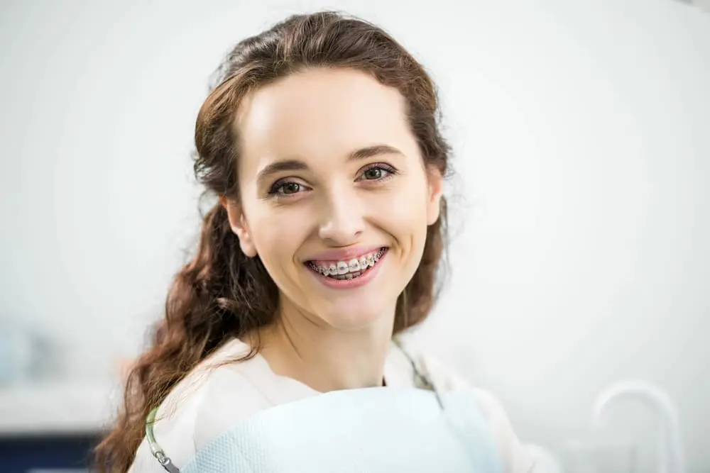a patient smiling at the camera with her metal braces from an orthodontist in Colleyville, TX